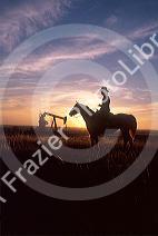 Silhouette of a cowboy on his horse with an oil well in the background at sunset in North Dakota.