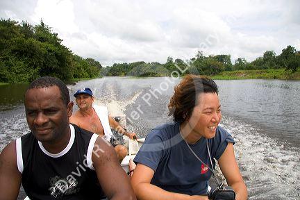 Tourists riding in a small river boat on the Arasa River in the Amazon jungle near Manaus, Brazil.