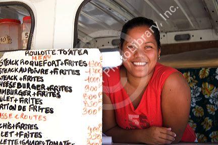 Tahitian woman working at a roulotte, food van on the island of Moorea.