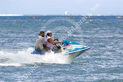 Tahitian men ride a jetski in the lagoon off the island of Moorea.