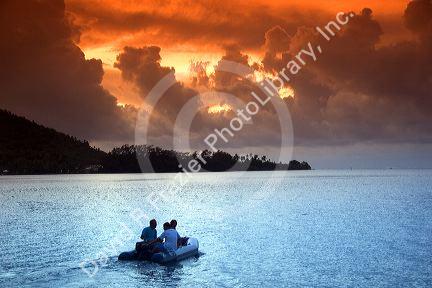 People in a small boat in the lagoon at sunset off the island of Moorea.