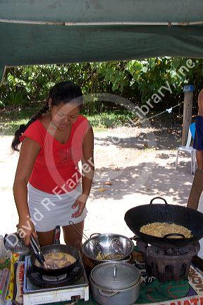 Tahitian woman cooking at a roulotte, food van on the island of Moorea.