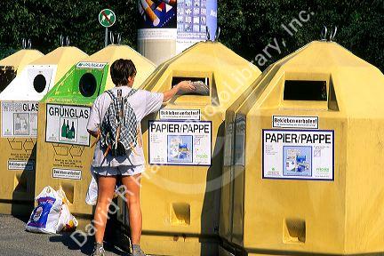 A woman depositing newspaper in recycling bins in Munich, Germany.