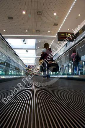 People stand on a moving walkway at the Denver International Airport, Colorado.