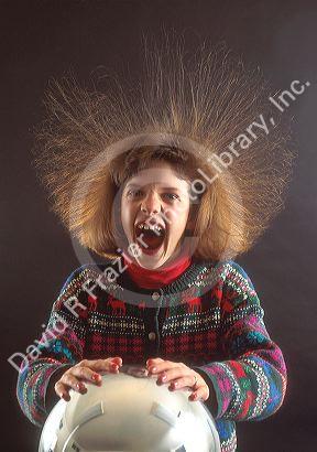 Girl with hair standing on end because of static electricity while touching a vandergraf generator.