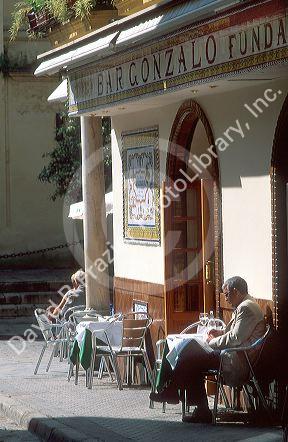 Man reading a news paper outside of a bar in Seville, Spain.