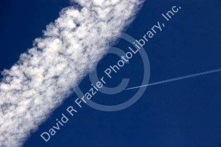 Vapor contrails from high flying jet aircraft.  The larger has been blown apart by the wind.