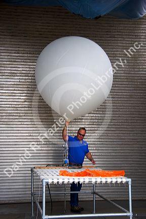 Meteorologist launching a weather balloon with a radiosonde sensor at the National Weather Service in Boise, Idaho.