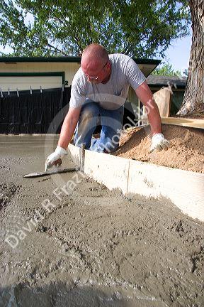 Worker leveling a newly poured concrete driveway in Boise, Idaho.
