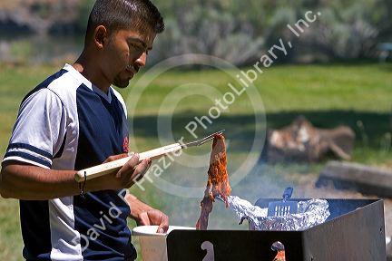 Mexican man grilling meat on a barbecue at Sandy Point Reservior near Boise, Idaho.