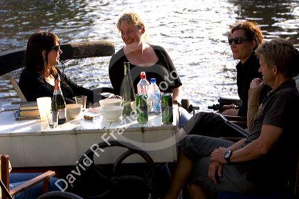 People socialize and dine along the Amstel River in Amsterdam, Netherlands.