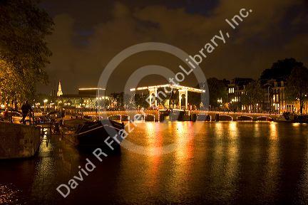 A drawbridge lit up at night on the Amstel River in Amsterdam, Netherlands.
