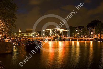 Skinny Magere drawbridge lit up at night on the Amstel River in Amsterdam, Netherlands.
