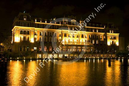 The Amset Hotel with lights at night along the Amstel River in Amsterdam, Netherlands.