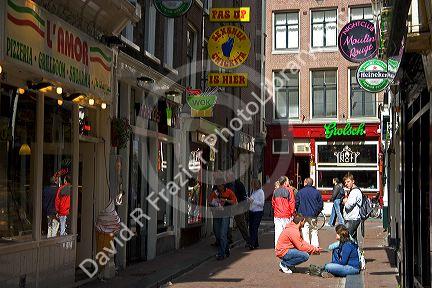 People and store fronts on a walking street in the Red Light District of Amsterdam, Netherlands.