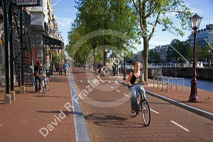People ride bicycles along the Amstel River in Amsterdam, Netherlands.