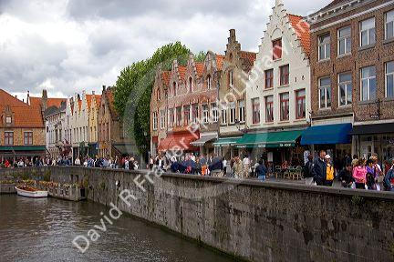 Storefronts and people along a canal in the city of Bruges in the province of West Flanders, Belgium.