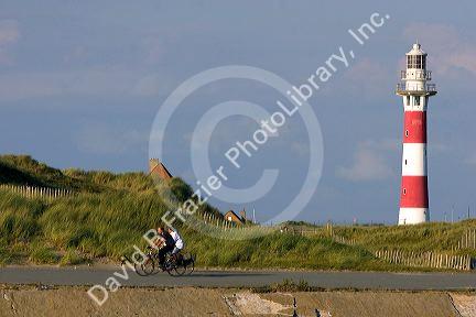 People ride bicycles past the Nieuwpoort Lighthouse at Nieuwpoort in the province of West Flanders, Belgium.