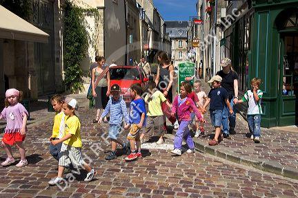 A group of adult supervised French children crossing the street at Bayeux in the region of Basse-Normandie, Normandy, France.