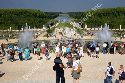 Tourists stand by fountains in the formal gardens of The Palace of Versailles at Versailles in the department of Yvelines, France.