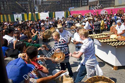 Baked bread in the shape of a skull covered in sugar being given away to a crowd of people celebrating the Day of Dead in the Zocalo in Mexico City, Mexico.