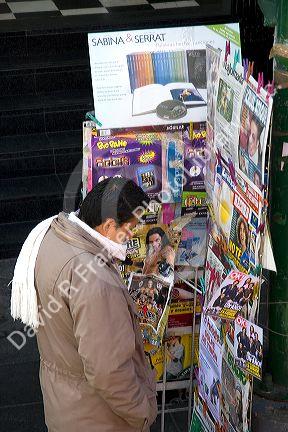 Mexican man browsing magazines at a kiosk in Mexico City, Mexico.