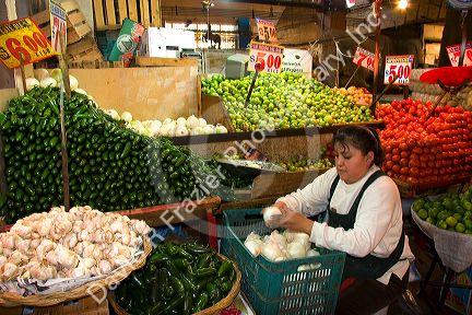 Vendor stocking onions at a produce stand at the Merced Market in Mexico City, Mexico.