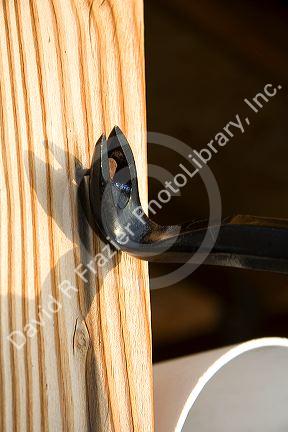 A cats paw crowbar pulling a nail out of a piece of wood.