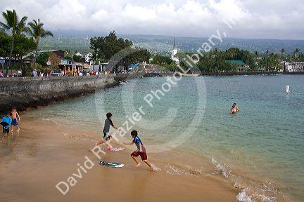 Children skimboarding at Kailua-Kona Bay on the Big Island of Hawaii.