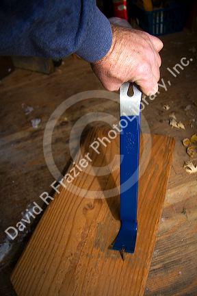 Flat pry bar pulling out a nail from a piece of lumber.