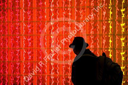 Man walking past a glass block wall lit with red light at Washington Dulles International Airport, Washington D.C.
