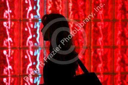 Woman walking past a glass block wall lit with red light at Washington Dulles International Airport, Washington D.C.