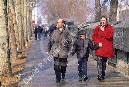 A family holding hands  walking together in Paris, France along the River Seine.