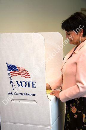 Woman voting on a paper ballot in a cardboard voting booth in Boise, Idaho.