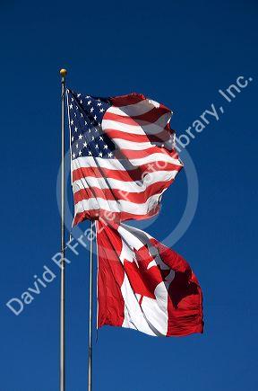 The Flag of the United States of America and the National Flag of Canada stand together on the international border at Port Huron, Michigan and Point Edward, Ontario.