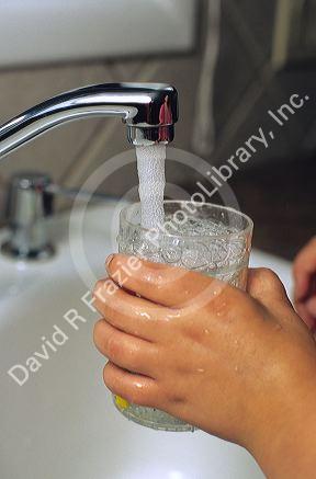 Child getting a glass of water from the kitchen faucet.