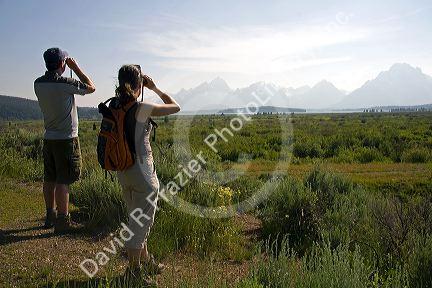 Tourists viewing the Teton Range and Jackson Lake with binoculars in Grand Teton National Park, Wyoming.