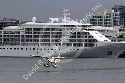Seaplane taking off in front of the Silversea Silver Shadow cruise ship at the Port of Vancouver in British Columbia, Canada.