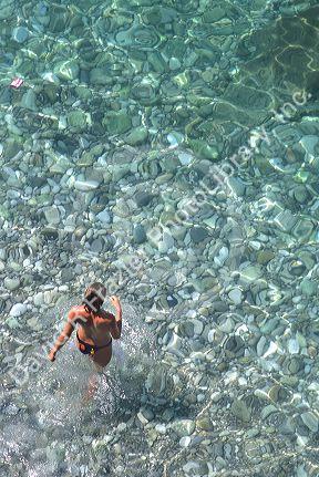 Bather enters the clear waters of the French Riviera and the Mediterranean.