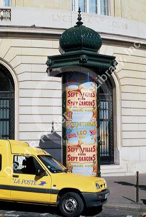 Kiosk with advertisements and a mail truck in Paris, France.