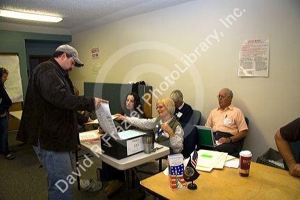 Voter putting paper ballot into a ballot box at a polling station in Boise, Idaho, USA.