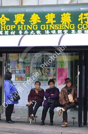 People wait at a bus stop in Chinatown, San Francisco, California.