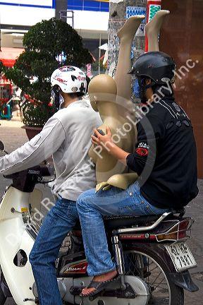 Vietnamese men ride a motorbike with a mannequin in Ho Chi Minh City, Vietnam.