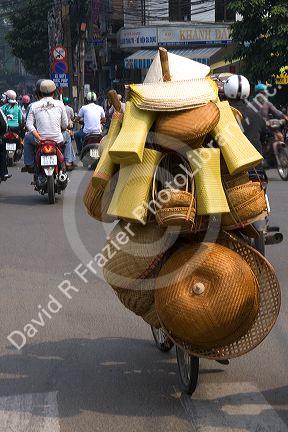 Vietnamese man riding a bicycle with many baskets in Ho Chi Minh City, Vietnam.
