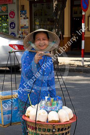 Vietnamese woman selling coconuts and bottled water on the street in Ho Chi Minh City, Vietnam.