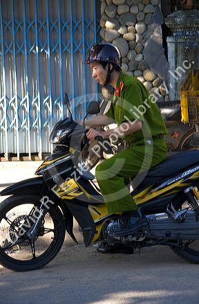 Vietnamese soldier riding a motorbike in Hoi An, Vietnam.