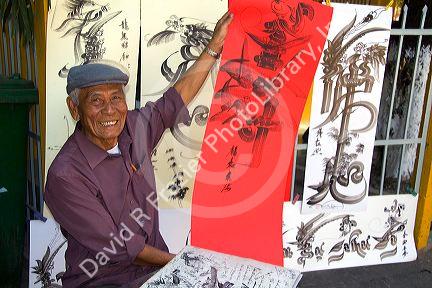 Vietnamese man drawing Chinese characters on red paper for good luck at the Giac Lam Pagoda Buddhist temple in Ho Chi Minh City, Vietnam.