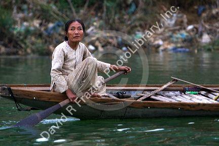 Vietnamese woman paddling a boat on the Perfume River at Hue, Vietnam.