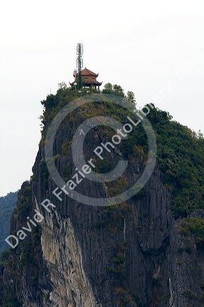 Limestone karast topped with an ancient structure and modern cell phone tower in Ha Long Bay, Vietnam.