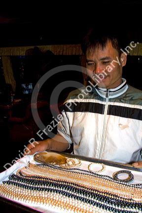 Vietnamese man selling pearl jewelry to tourists on a boat in Ha Long Bay, Vietnam.